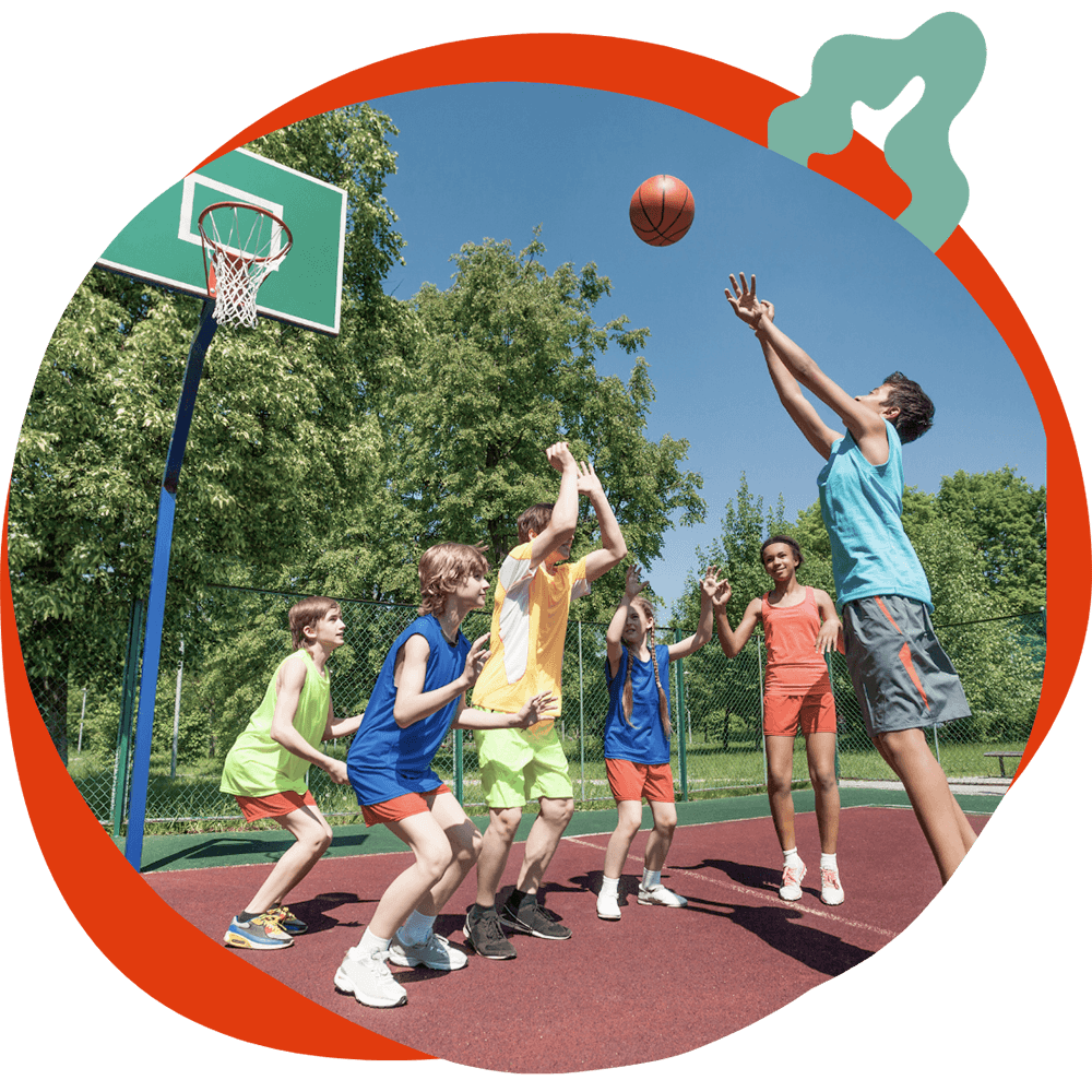 Un gruppo di ragazzi che gioca a basket all'aperto in una giornata di sole, durante un'attività sportiva del corso estivo Move Your Summer