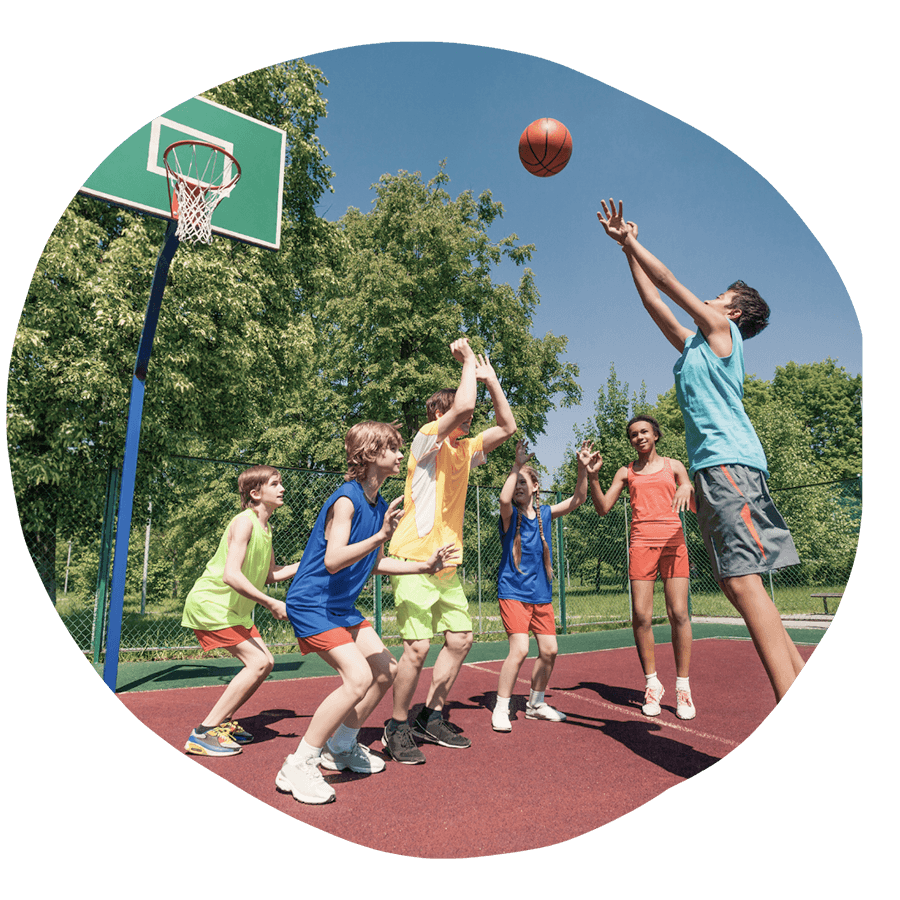 Un gruppo di ragazzi che gioca a basket all'aperto in una giornata di sole, durante un'attività sportiva del corso estivo Move Your Summer