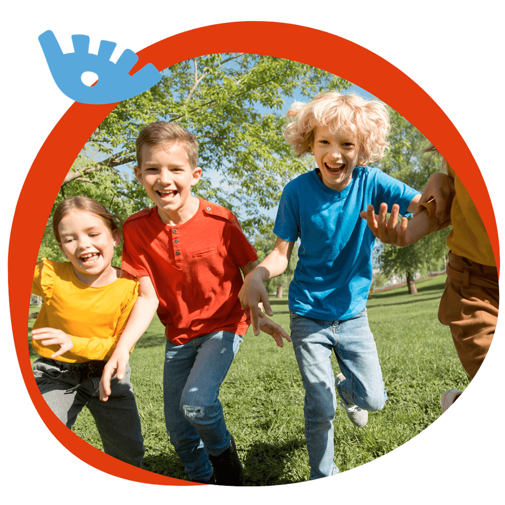 Tre bambini che corrono e ridono in un parco verde durante un'attività all'aperto del corso estivo Move Your Summer