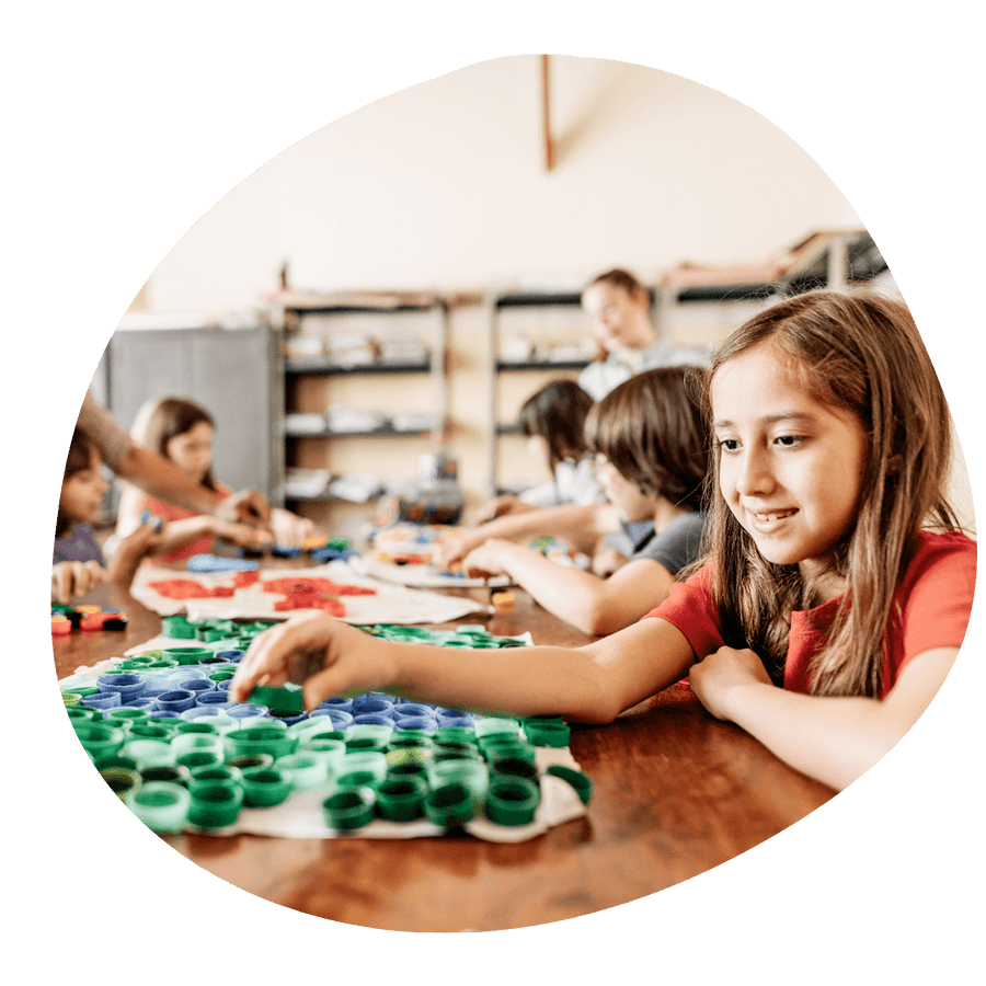 Una bambina sorridente che lavora a un laboratorio creativo con materiali colorati, durante un'attività Artlish del corso estivo Move Your Summer