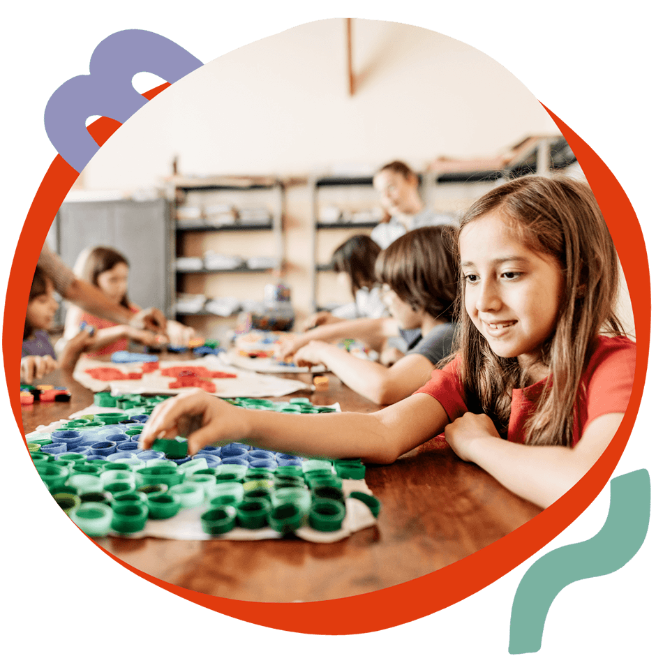 Una bambina sorridente che lavora a un laboratorio creativo con materiali colorati, durante un'attività Artlish del corso estivo Move Your Summer