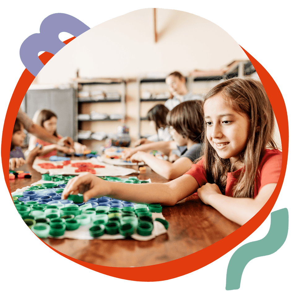 Attività 9 Una bambina sorridente che lavora a un laboratorio creativo con materiali colorati, durante un'attività Artlish del corso estivo Move Your Summer