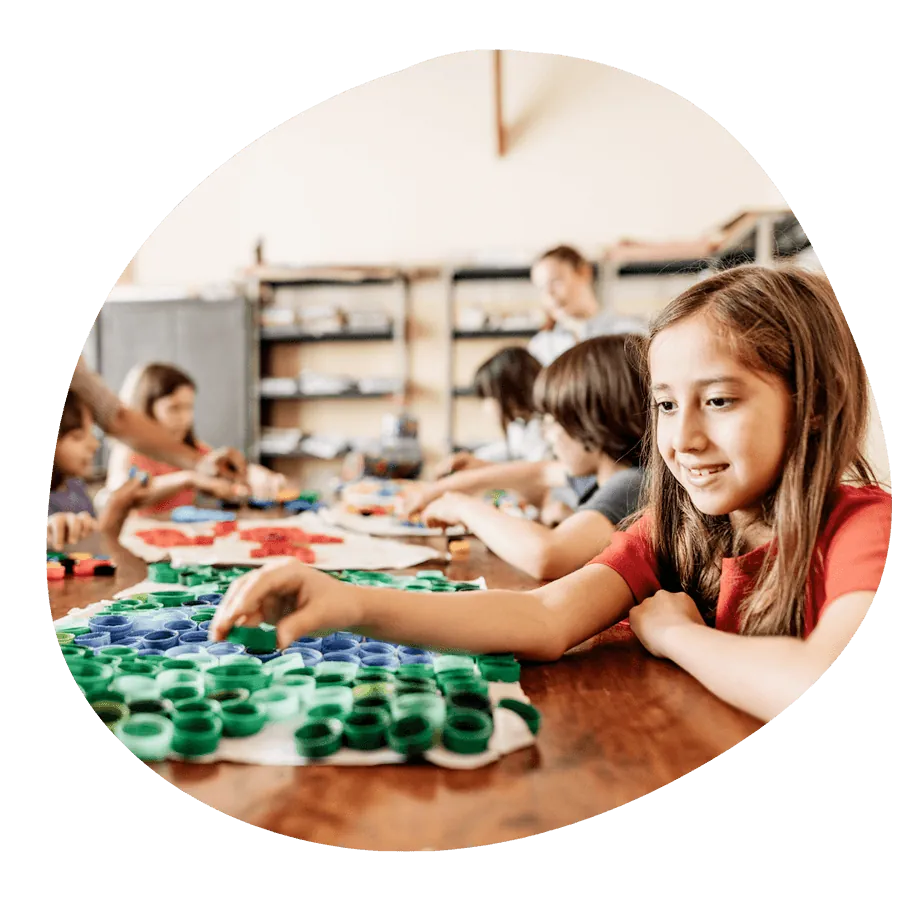 Una bambina sorridente che lavora a un laboratorio creativo con materiali colorati, durante un'attività Artlish del corso estivo Move Your Summer