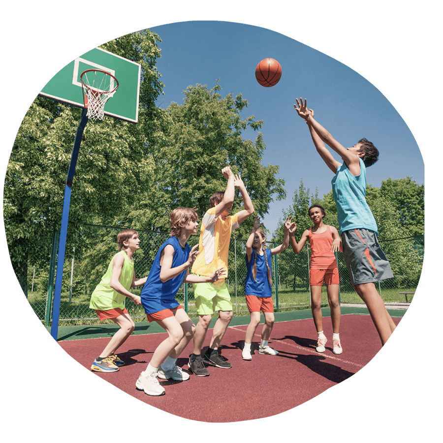 Un gruppo di ragazzi che gioca a basket all'aperto in una giornata di sole, durante un'attività sportiva del corso estivo Move Your Summer